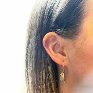 Gold feather earrings worn