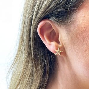 Gold starfish earrings worn