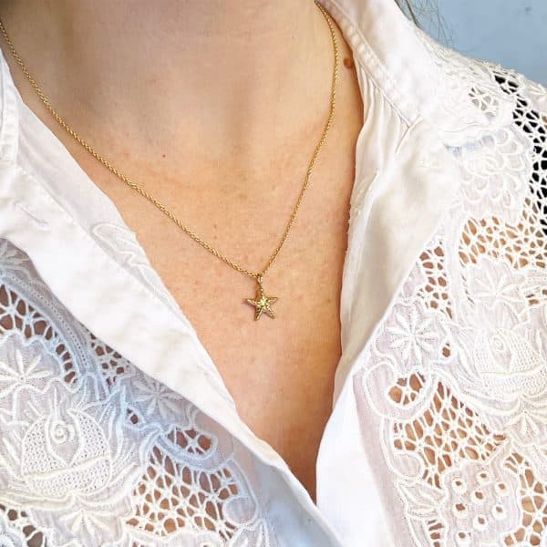 Gold starfish necklace worn
