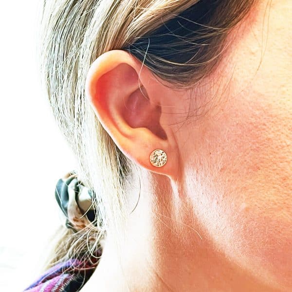 Gold disc stud earrings worn